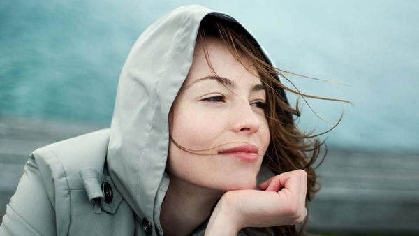 Vrouw zit in de wind, rustend met haar kin op haar hand.