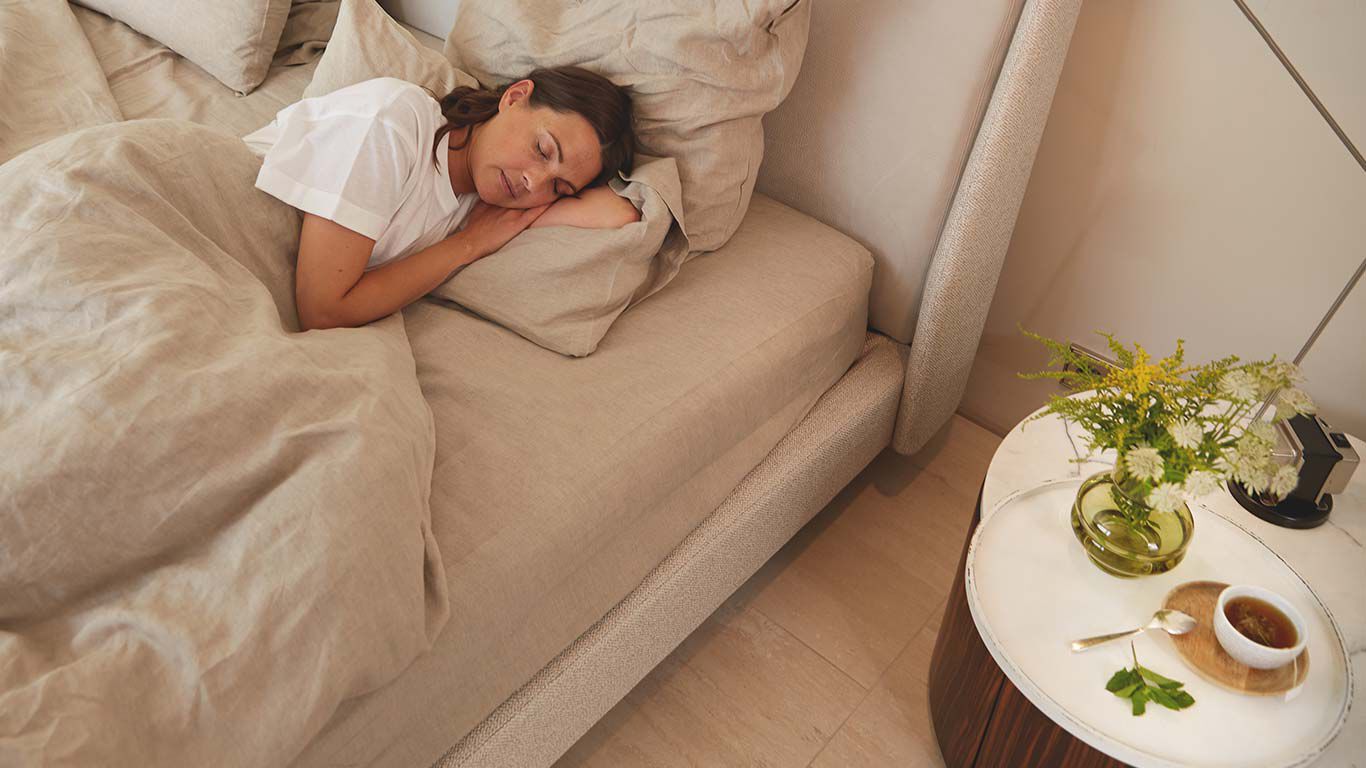 Vrouw slaapt op haar zij in haar bed.