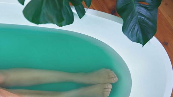 Vue aérienne de jambes dans une baignoire d'eau bleu-vert.