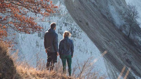 La femme et l'homme se tiennent dans la nature. L'image montre une vue arrière des deux.