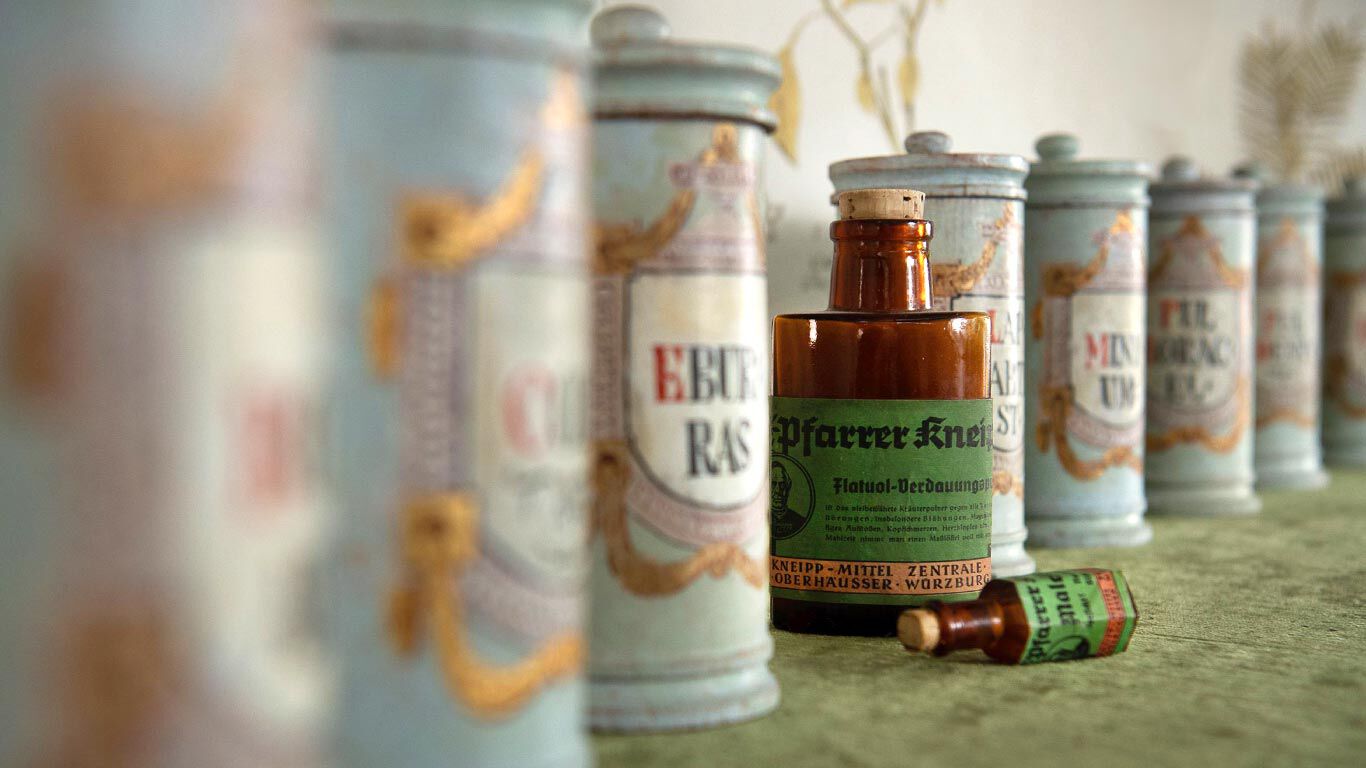 Oude apothekerspotten met daartussen een fles Flatuol van Kneipp