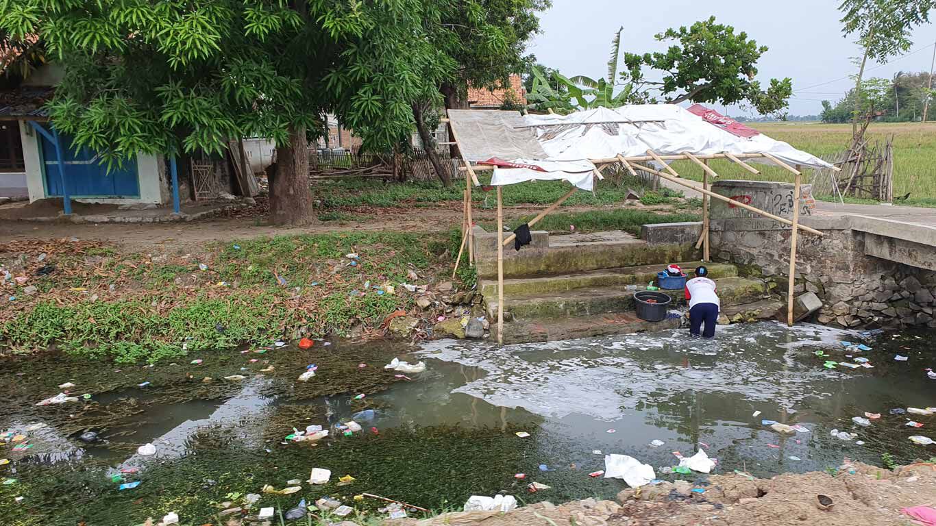 Indonesische rivier vol met plastic afval waarin wasgoed wordt gewassen.