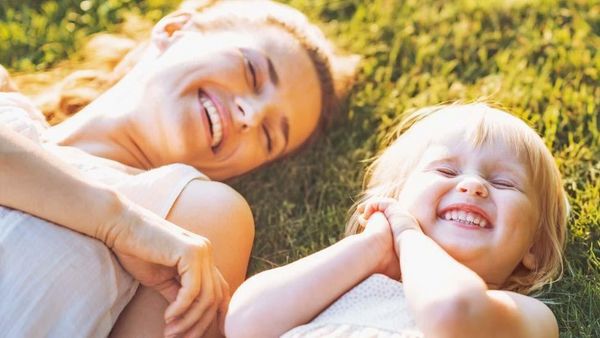 La mère et la fille sont allongées dans l'herbe en riant.