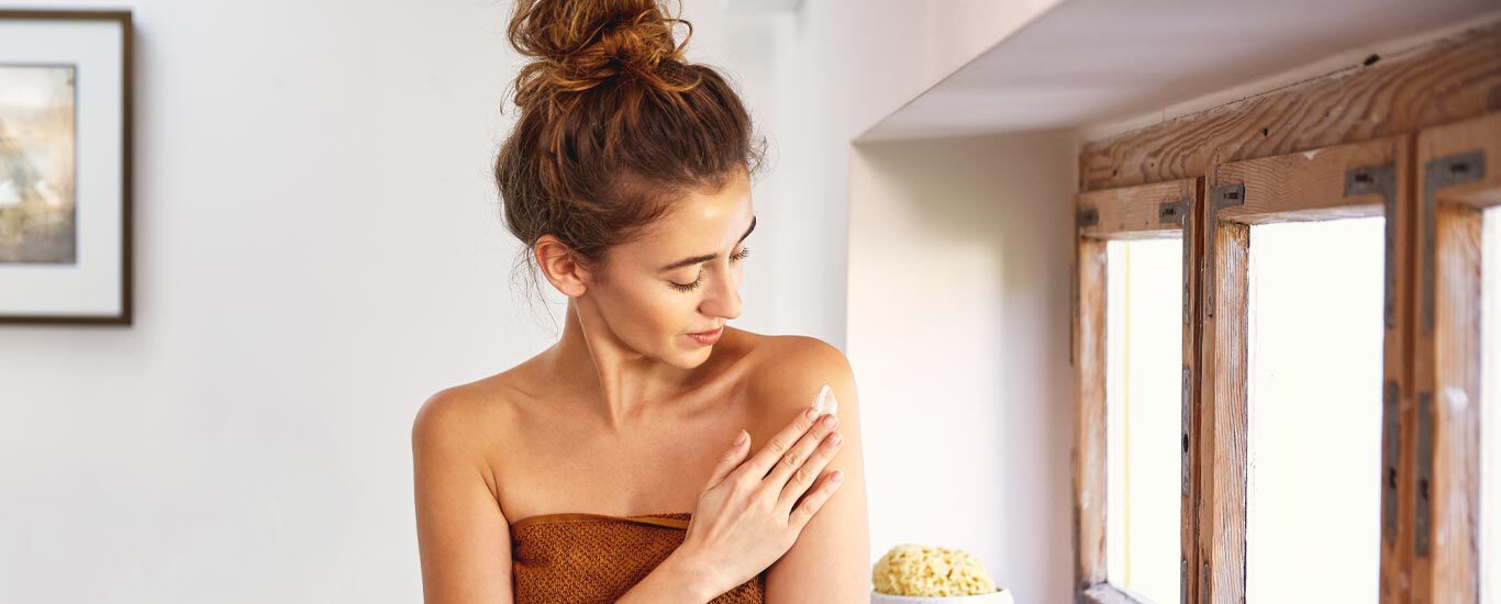 Femme avec un chignon en train d'appliquer de la crème. 