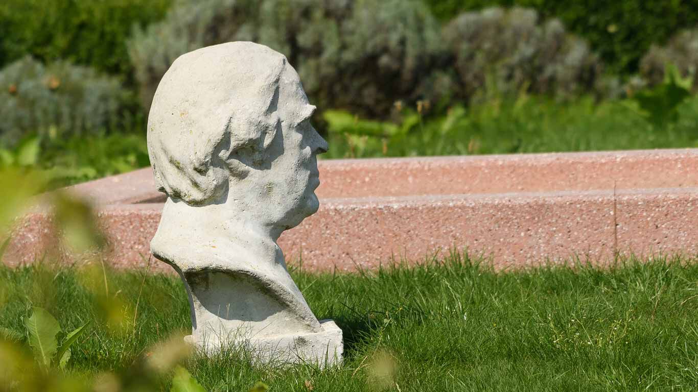 Statue de Sebastian Kneipp dans l'herbe verte.