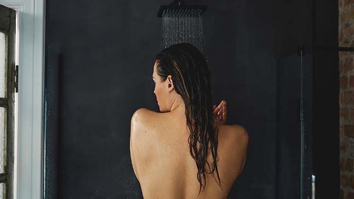 Achteraanzicht van een vrouw die een douche neemt. 