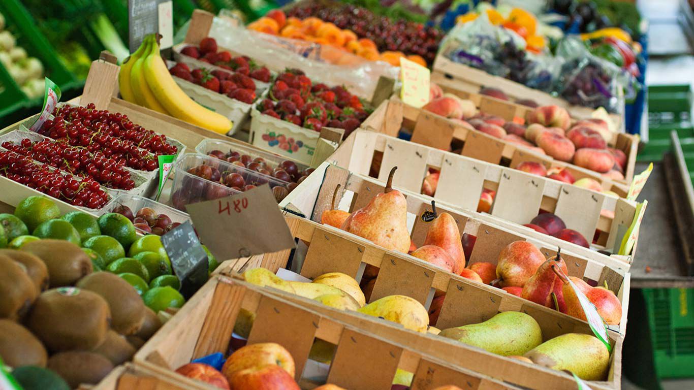 Kleurrijk fruit in houten kistjes bij een marktkraam.