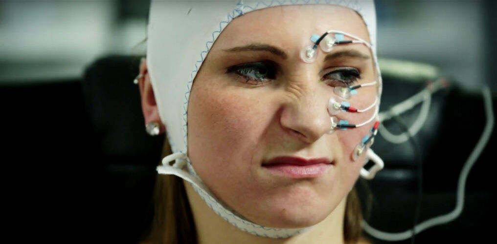 Woman with sensors on her head and face contorts her face