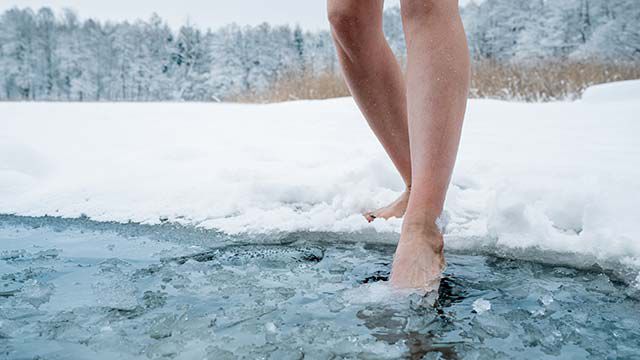 Gros plan sur des jambes qui entrent dans de l'eau glacée.