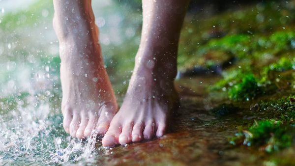 Gros plan de pieds sur une surface moussue. Éclaboussures d'eau sur le bord gauche de l'image.