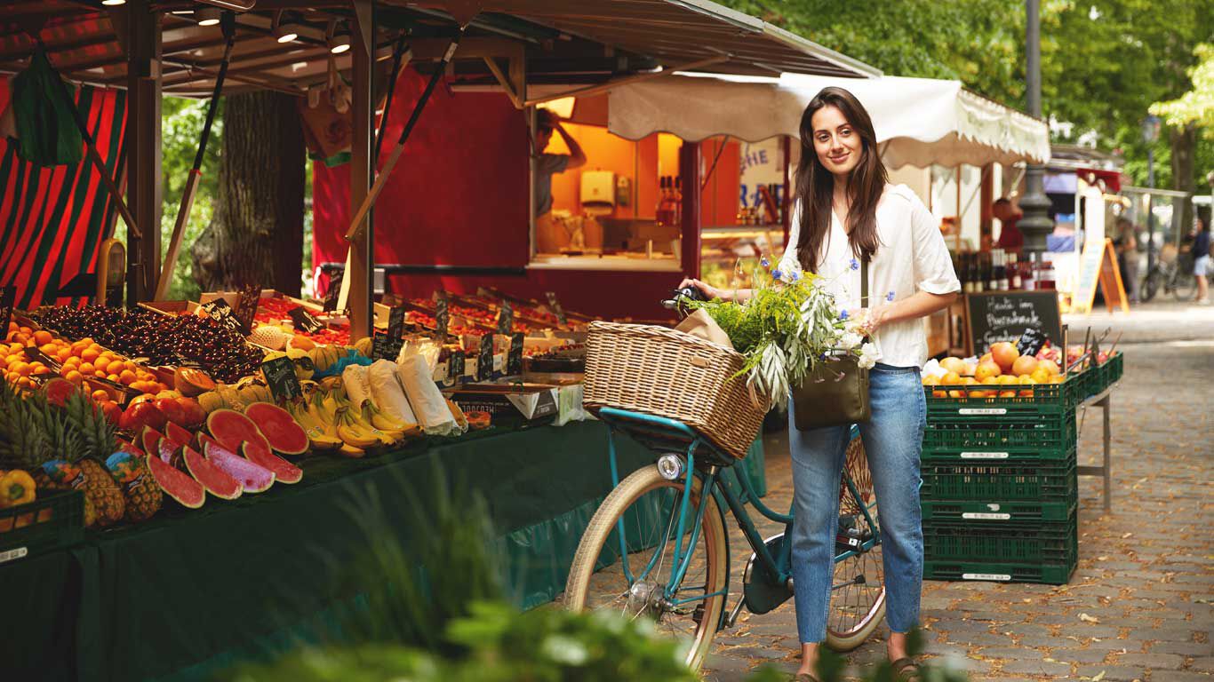 Vrouw duwt haar fiets over de wekelijkse markt.