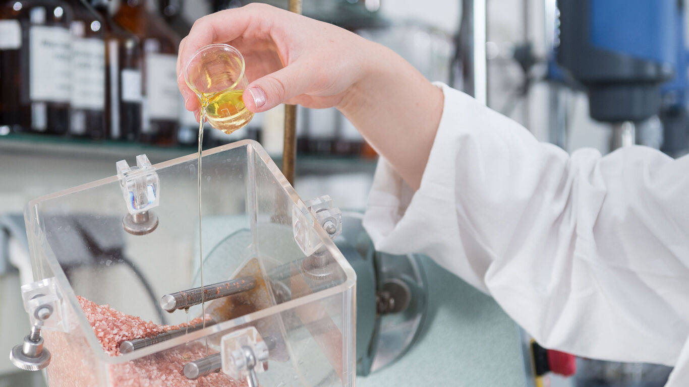 Een vrouw giet plantaardige olie over badzout in het lab
