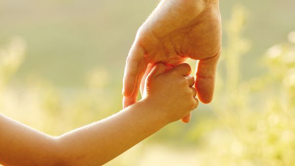 De hand van het kind pakt de hand van de volwassene vast.