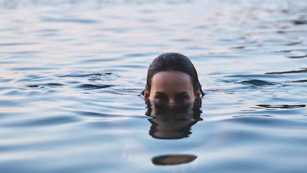 Vrouw duikt tot haar hoofd in een meer.