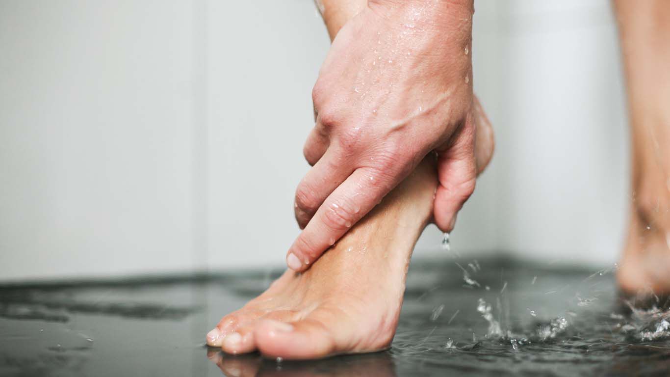 Gros plan sur un pied en train d'être lavé sous la douche. 