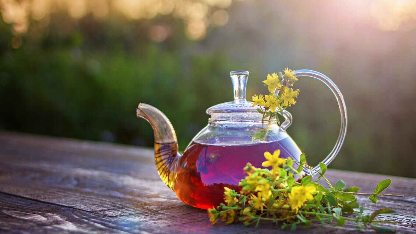 Glazen theepot met kruidenthee op een houten tafel.