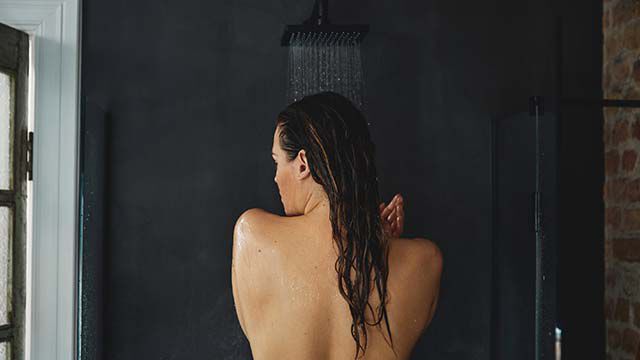 Achteraanzicht van een vrouw die een douche neemt. 