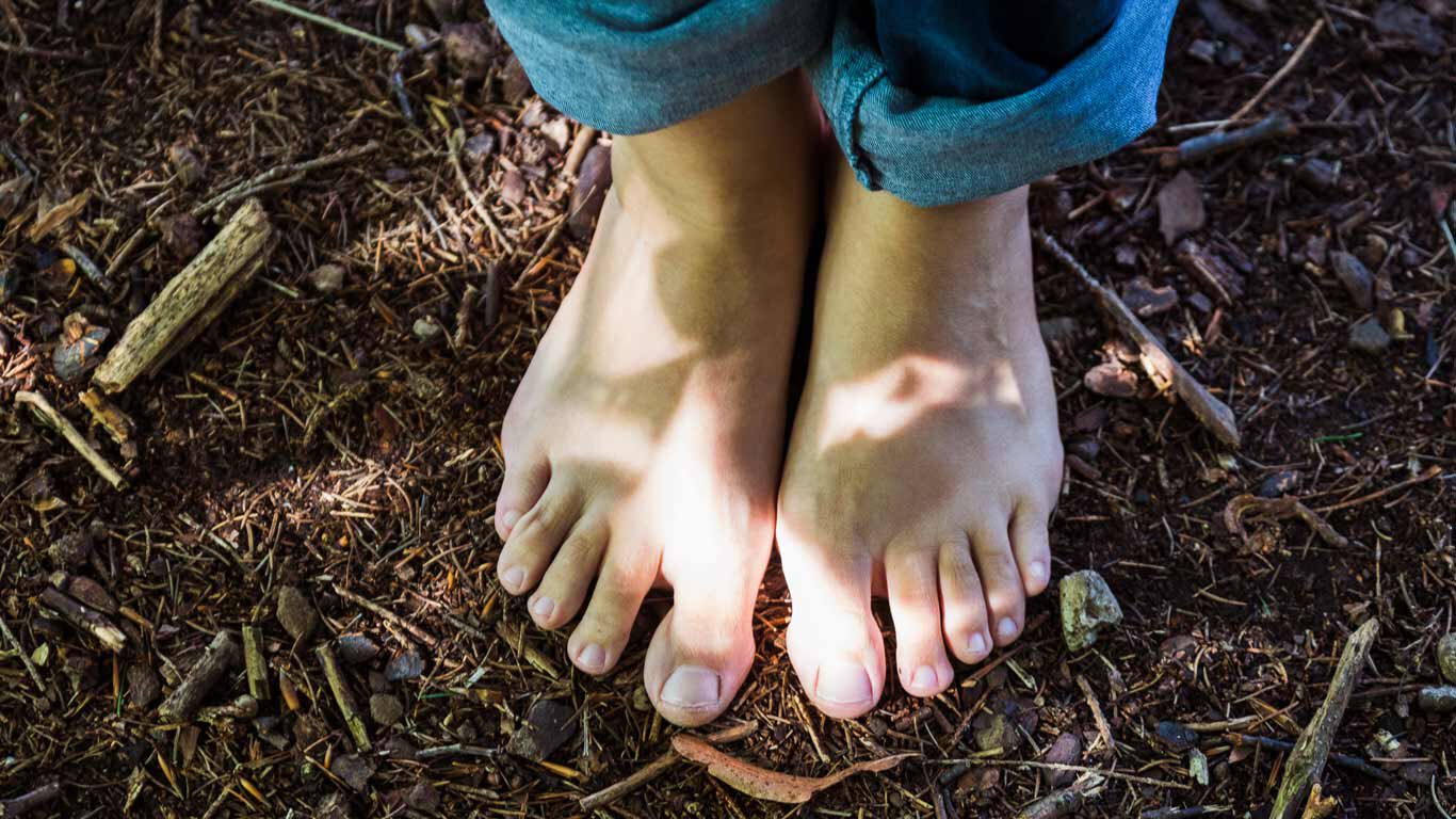 Blote voeten op de bosgrond.