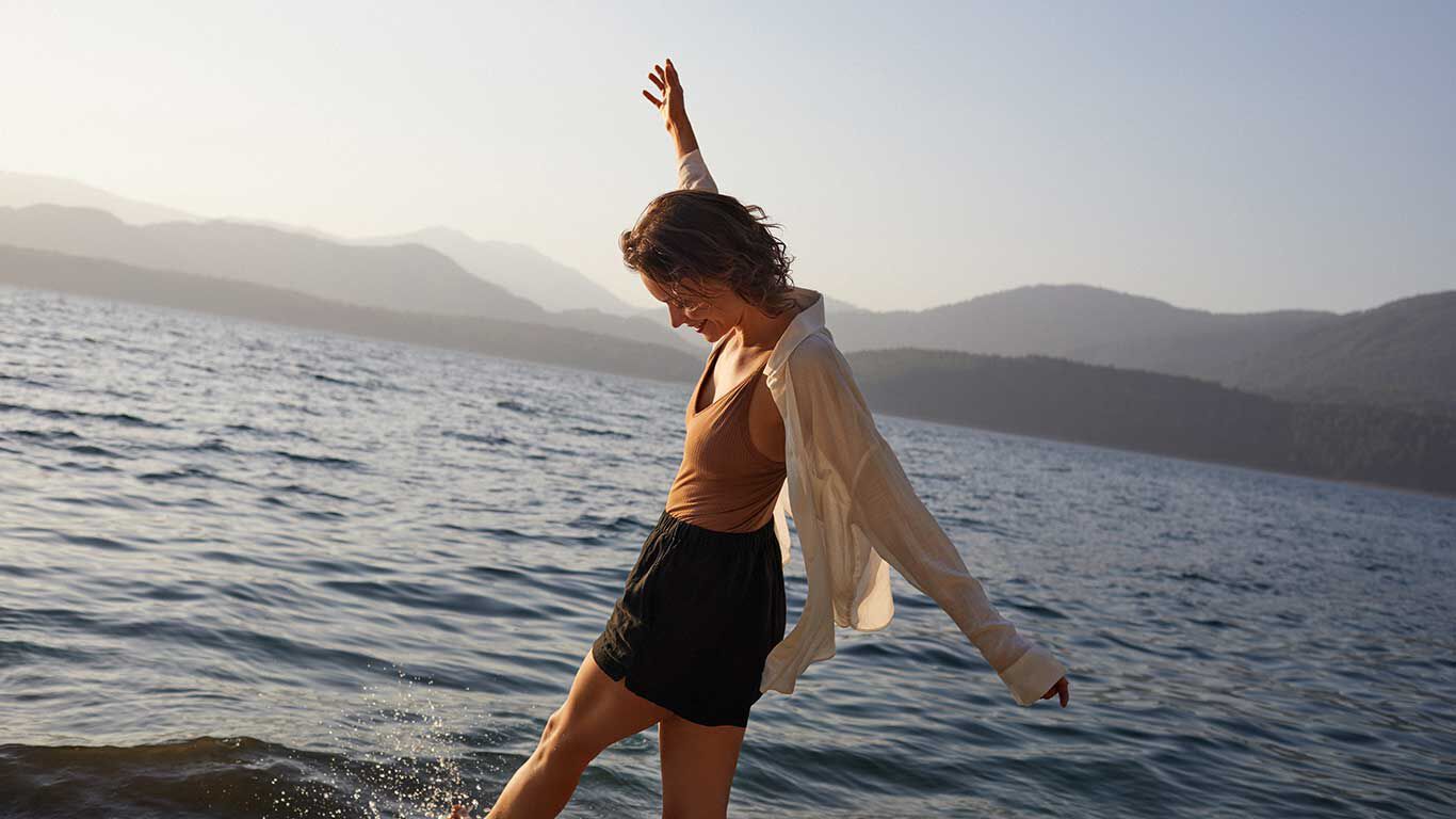 Femme heureuse &eacute;claboussant l&rsquo;eau de mer avec ses jambes.