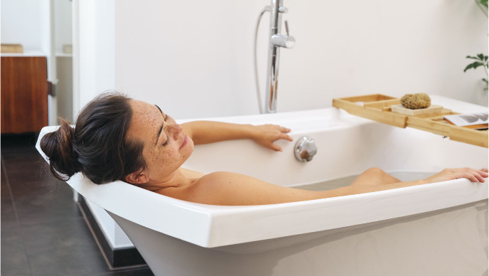 Sustainable bathroom: Woman relaxes with a three-quarter Kneipp bath.