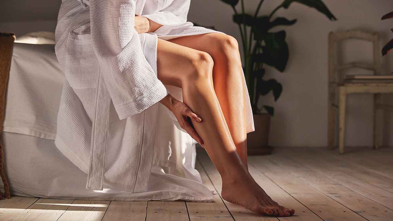 Une femme prend soin de ses jambes avec de l'huile s&egrave;che.