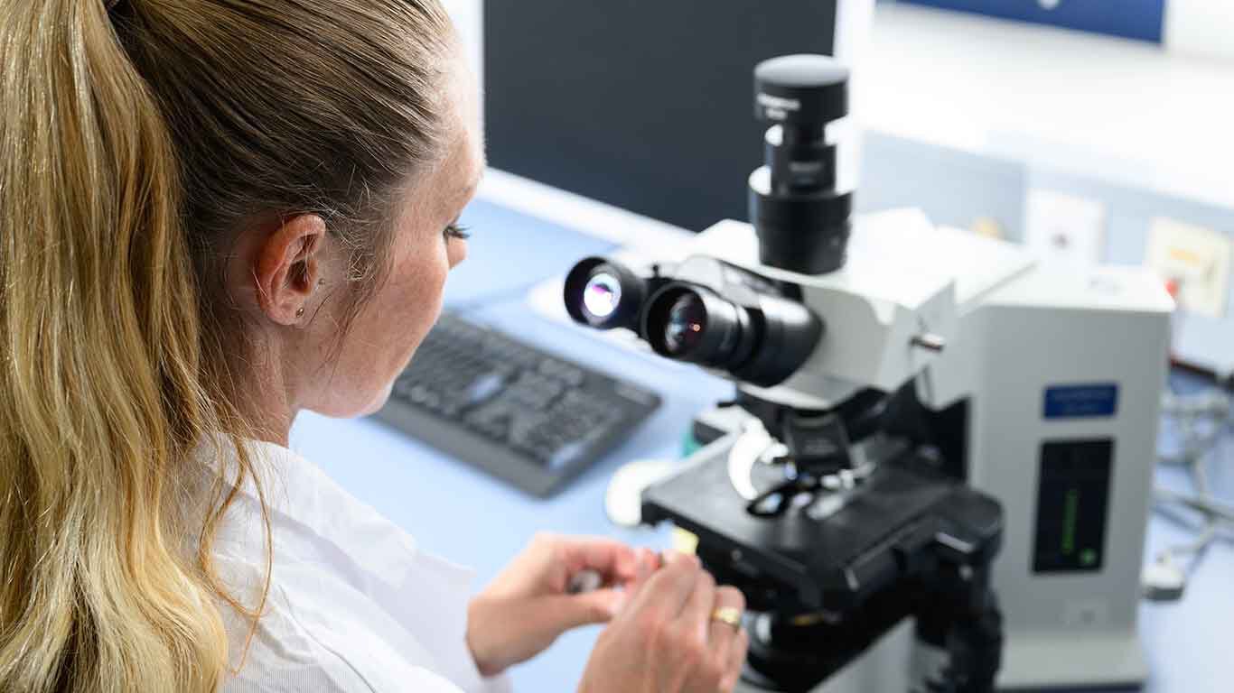 Une femme devant un microscope.