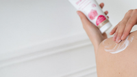 Vrouw van achteren die lotion op haar schouder aanbrengt. Kneipp bodylotion op de achtergrond. 