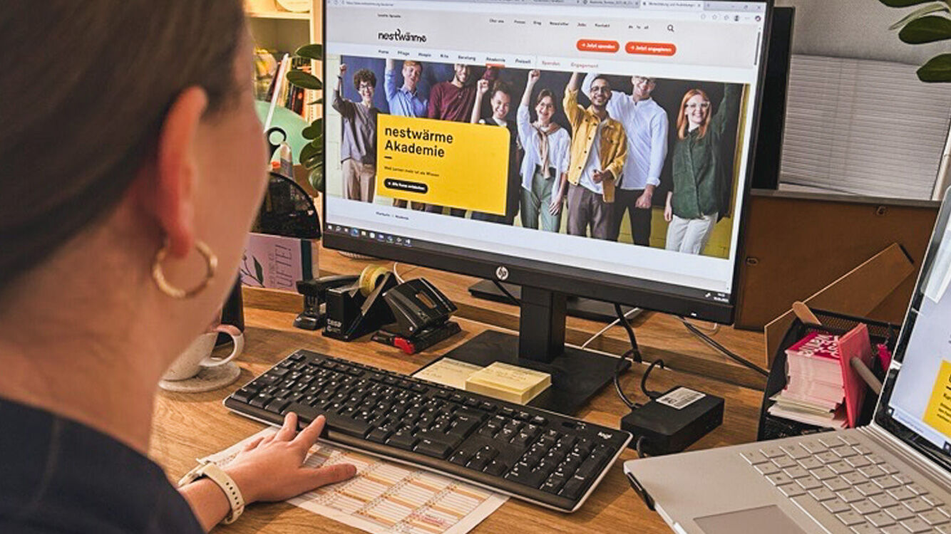 Frau sitzt am Computer und sieht sich nestwärme Webseite an