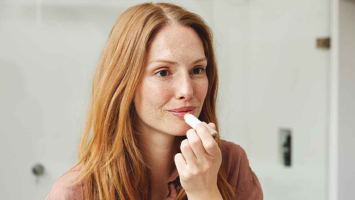 Frau trägt getönte Lippenpflege auf