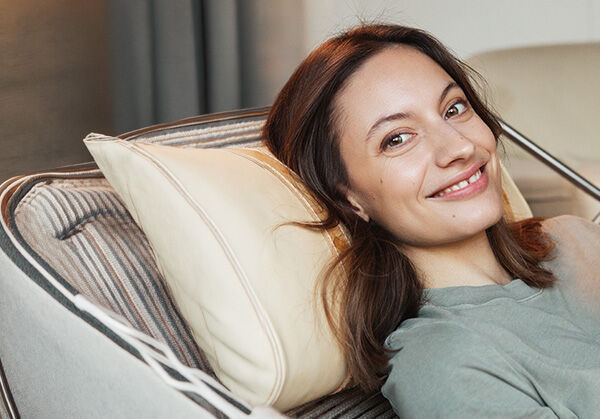 Frau liegt l&auml;chelnd auf dem Sofa.