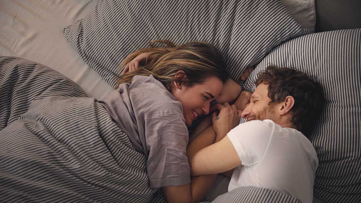 Mann und Frau kuscheln zusammen im Bett
