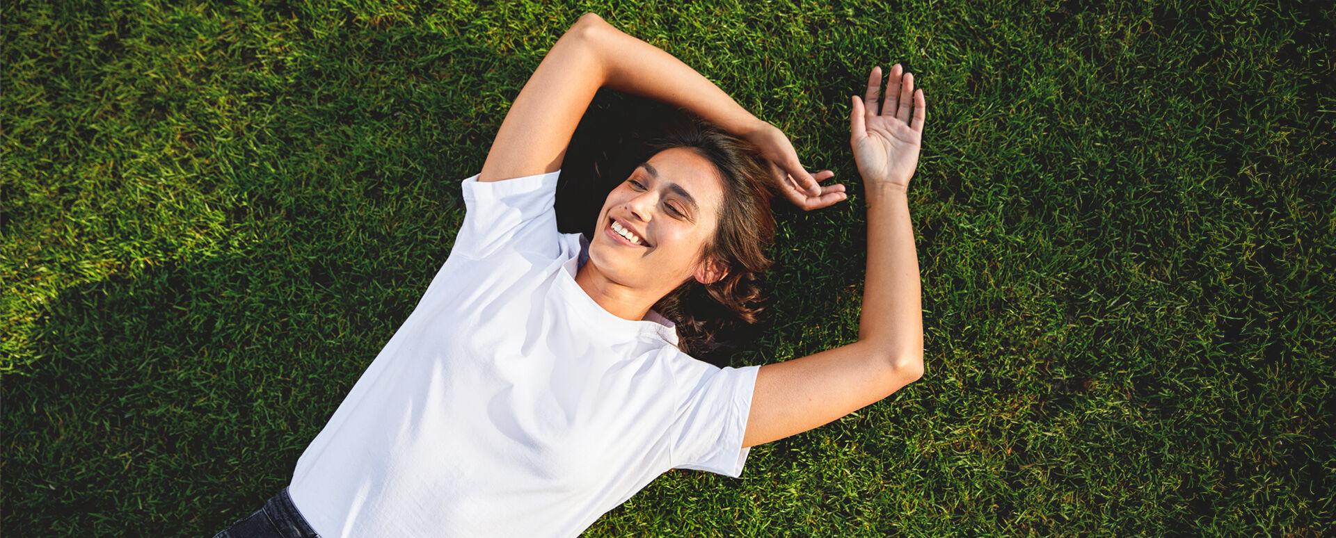 Frau liegt auf der Wiese und genie&szlig;t die Sonne