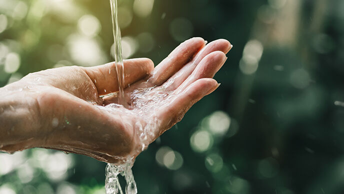 Hand fängt Wasserstrahl auf. 