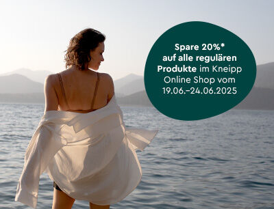 Frau steht im Meer im sommerlichen Badeoutfit.