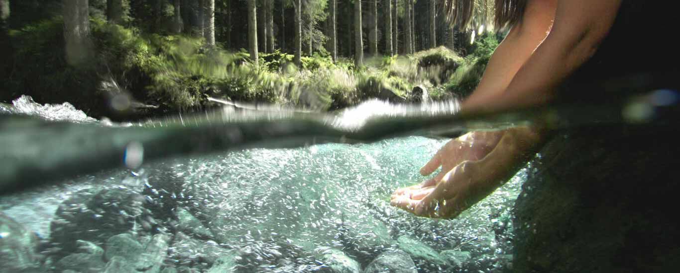 Hände, die in seichtes Wasser gleiten.