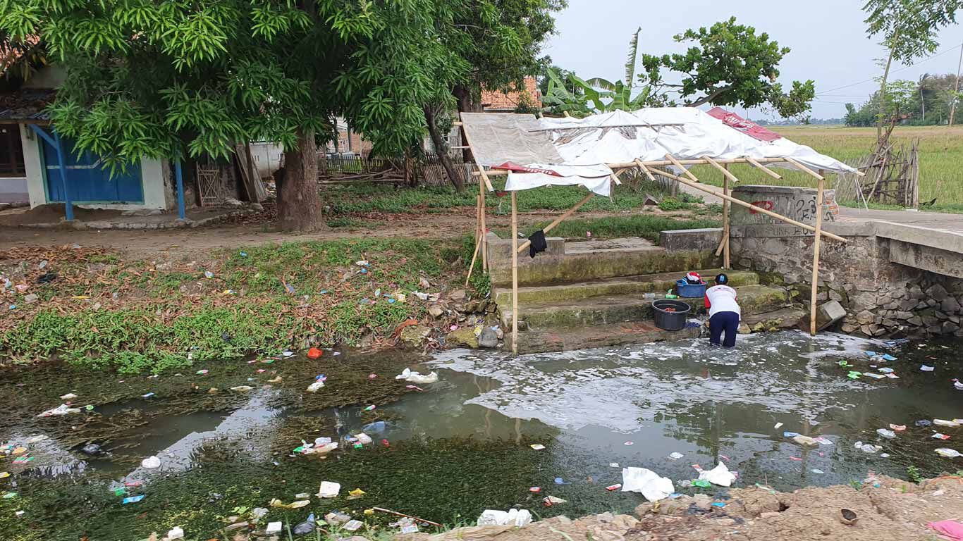 Indonesischer Fluss voller Plastikmüll, in dem Wäsche gewaschen wird.