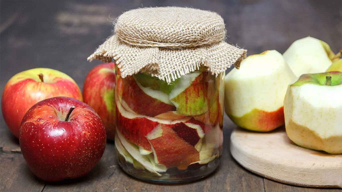 Glas mit Apfelstückchen, daneben Äpfel.