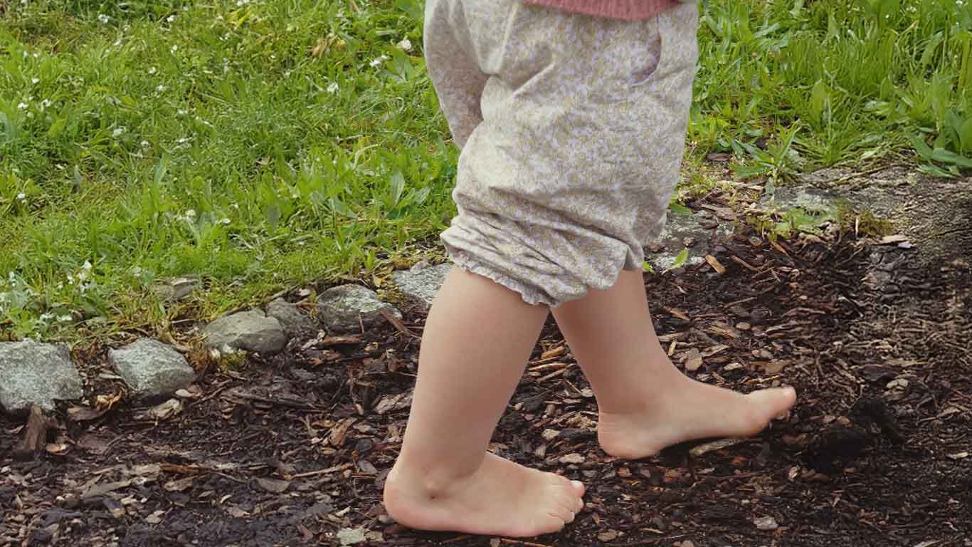 Kinderfüße laufen über Rindenmulch. 