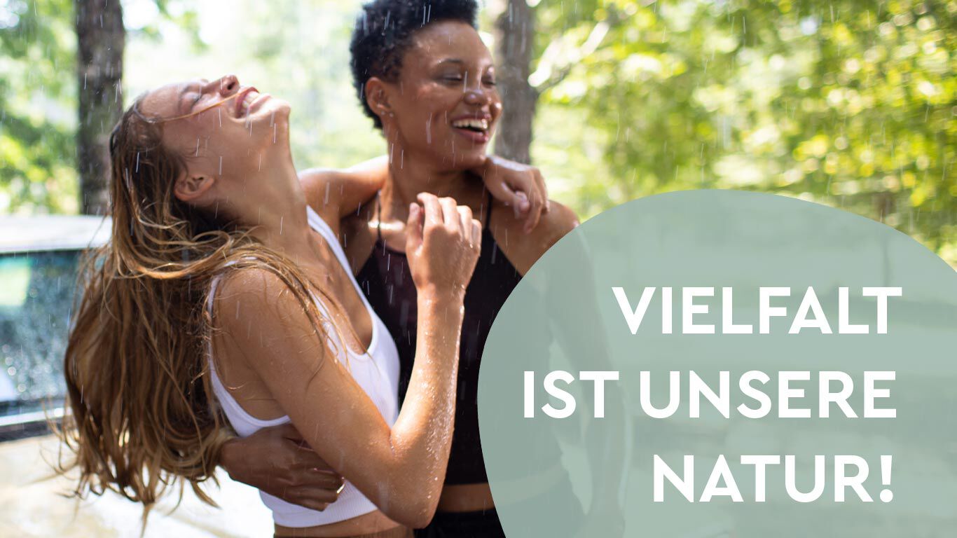 Zwei Frauen unterschiedlicher ethnischer Herkunft umarmen sich. Das Bild ist ein Symbol für die Aussage "Vielfalt ist unsere Natur!"