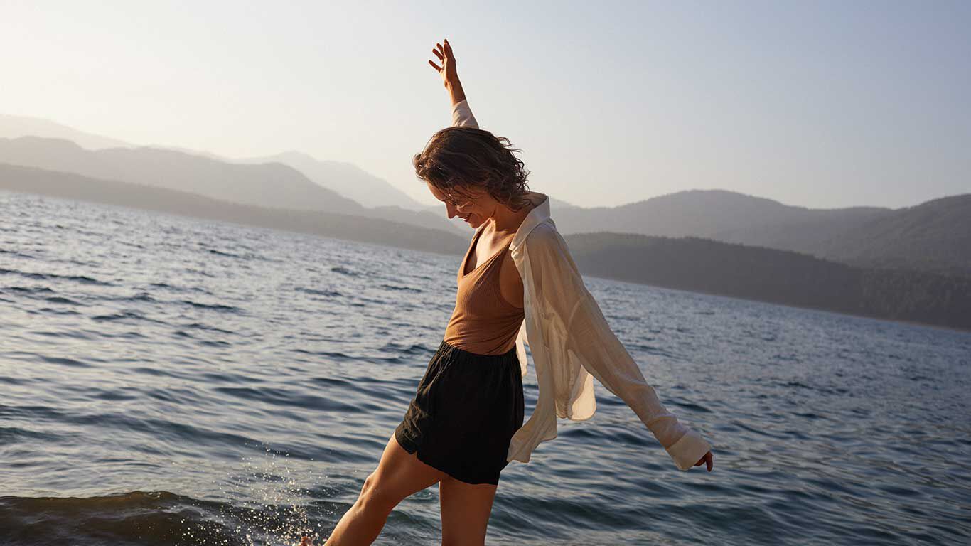 Glückliche Frau spritzt mit ihren Beinen im Meer. 