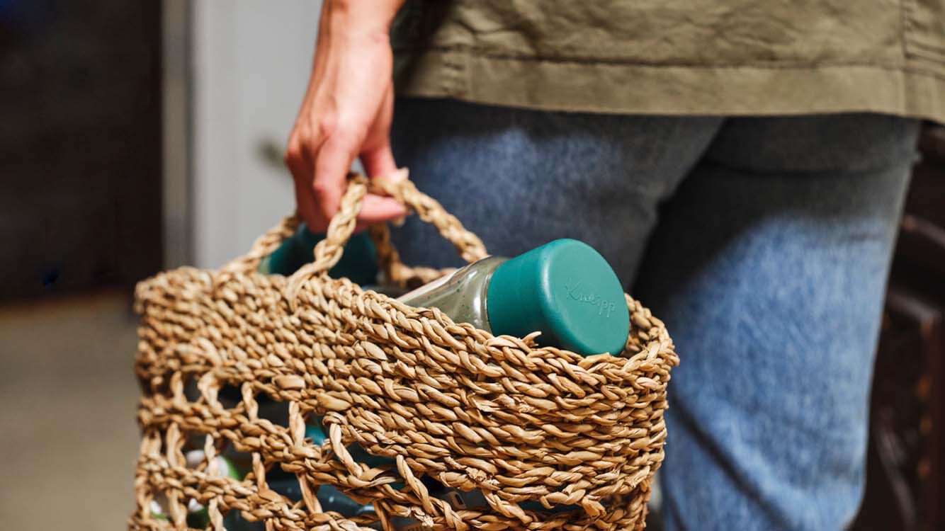 Person trägt eine geflochtene Tasche mit Kneipp Verpackung..