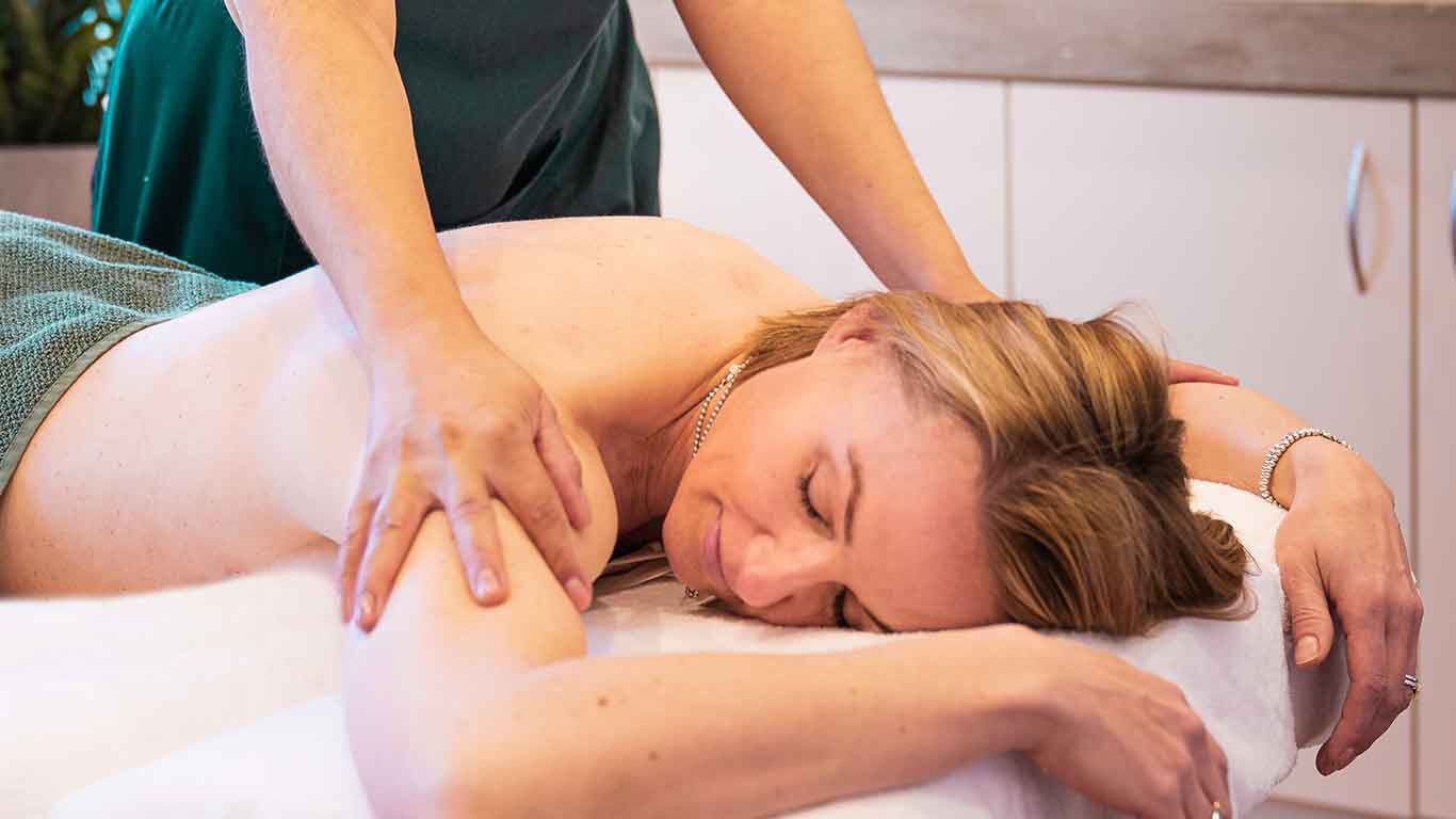 Frau auf Massageliege während einer Massage.