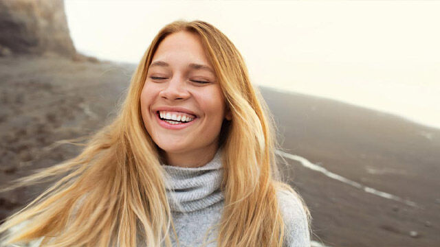 Blondes Mädchen lacht mit geschlossenen Augen. 