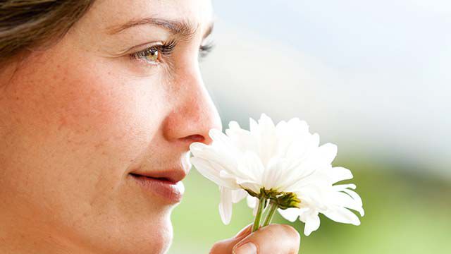  Frau riecht an einer Blume.