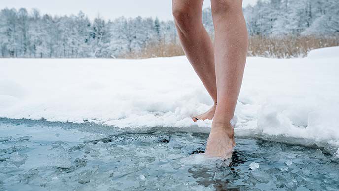 Nahaufnahme von Beinen, die Eiswasser betreten.