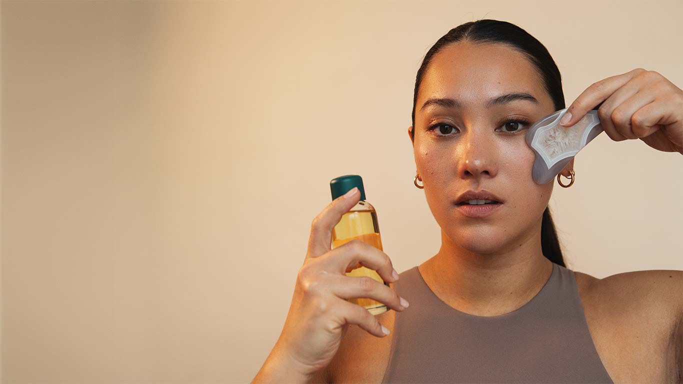 Frau mit Öl und Gua Sha Stein in der Hand. 