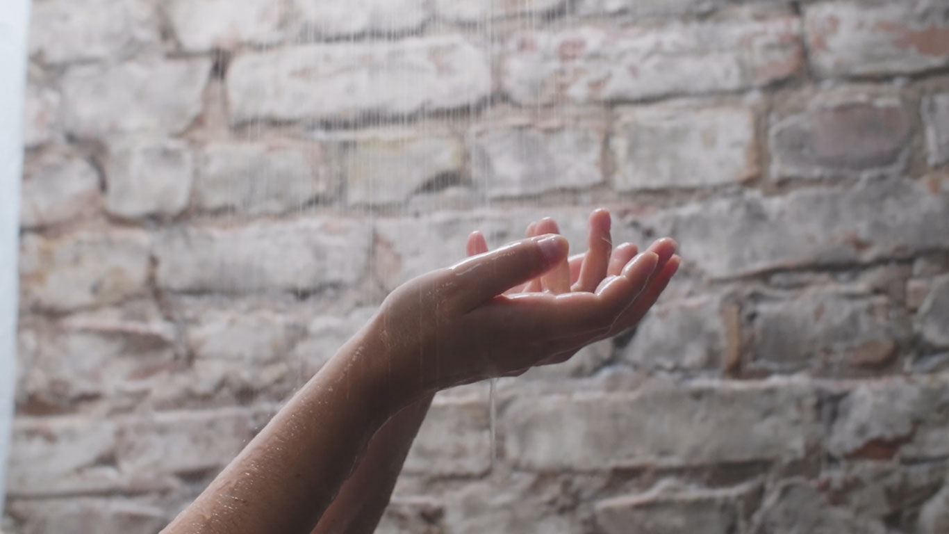 Video: Nahaufnahme von Händen unter dem Wasserstrahl einer Dusche.