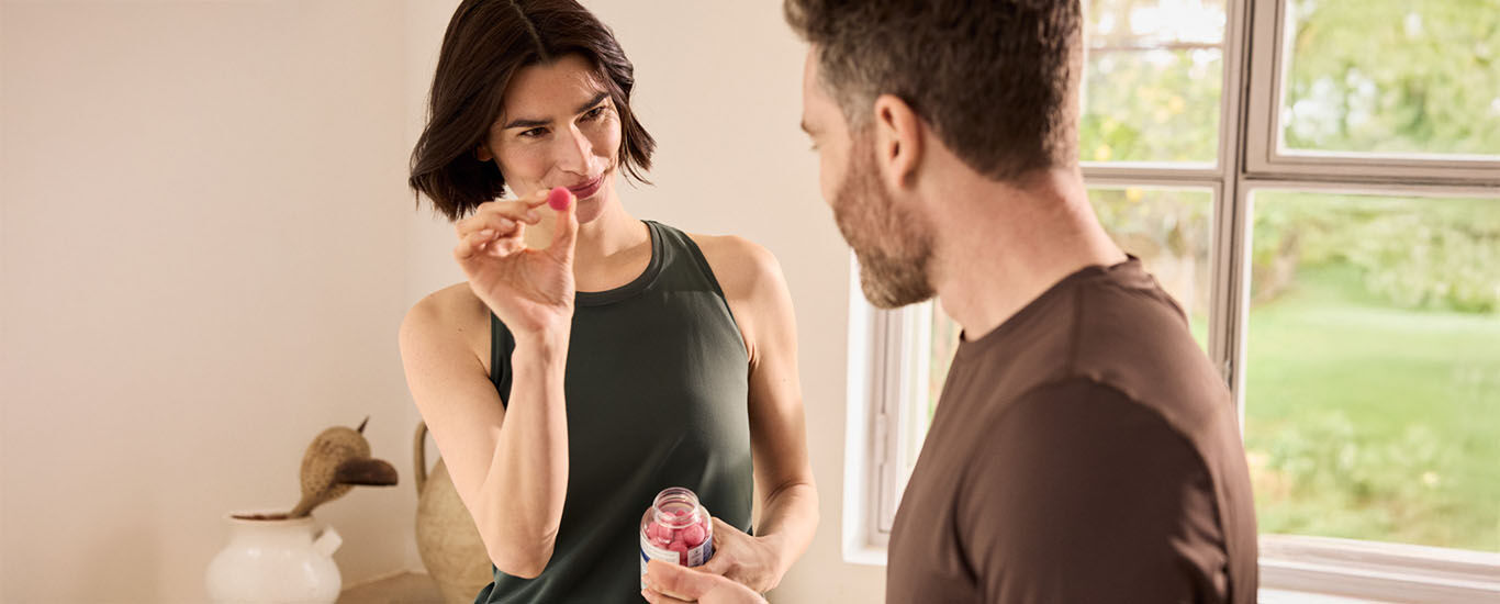 Mann und Frau stehen in der K&uuml;che, Frau h&auml;lt eine Kneipp Magnesium-Gummies Packung in der Hand.