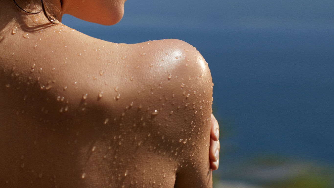 Frau in Rückenansicht mit Wasserstropfen auf der Haut.