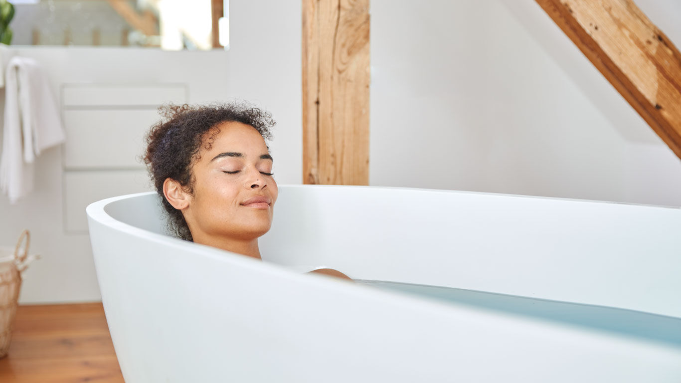 Dunkelhaarige Frau entspannt in der Badewanne.